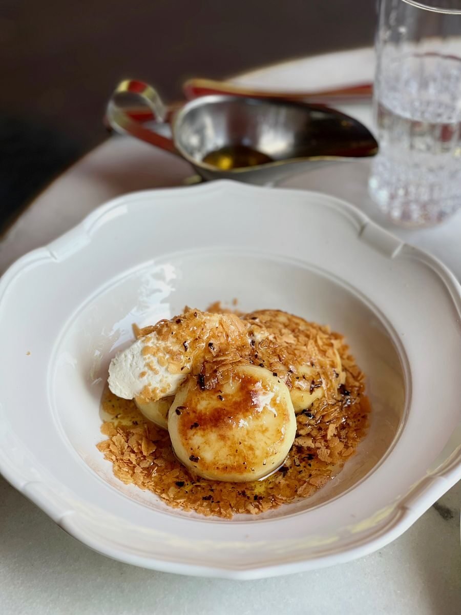 Elegant plated dessert with caramelized sauce and cream served in a white dish.