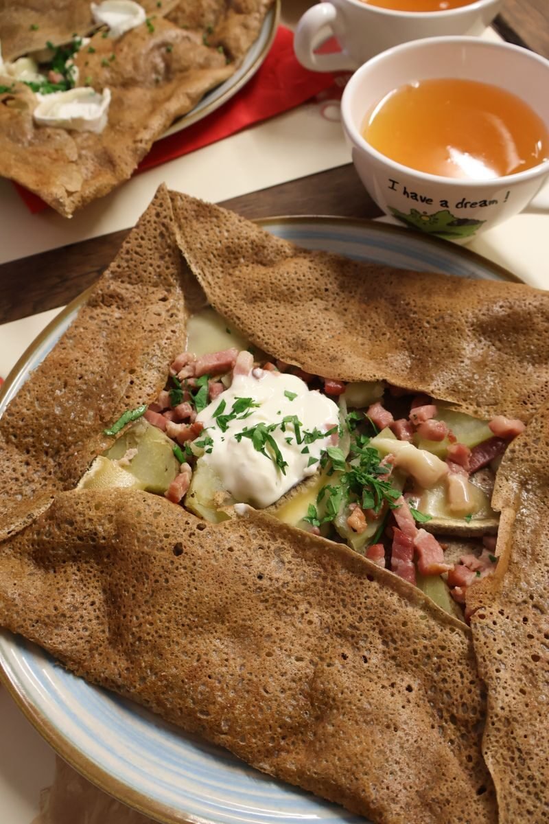 Delicious savory galette with toppings, surrounded by cups of tea at Mont Saint-Michel.