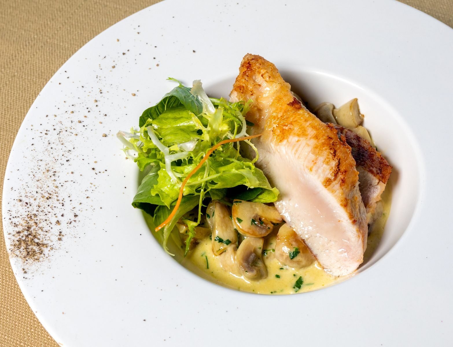 Delicious chicken dish with mushrooms and salad on a white plate. Perfect for gourmet food lovers.