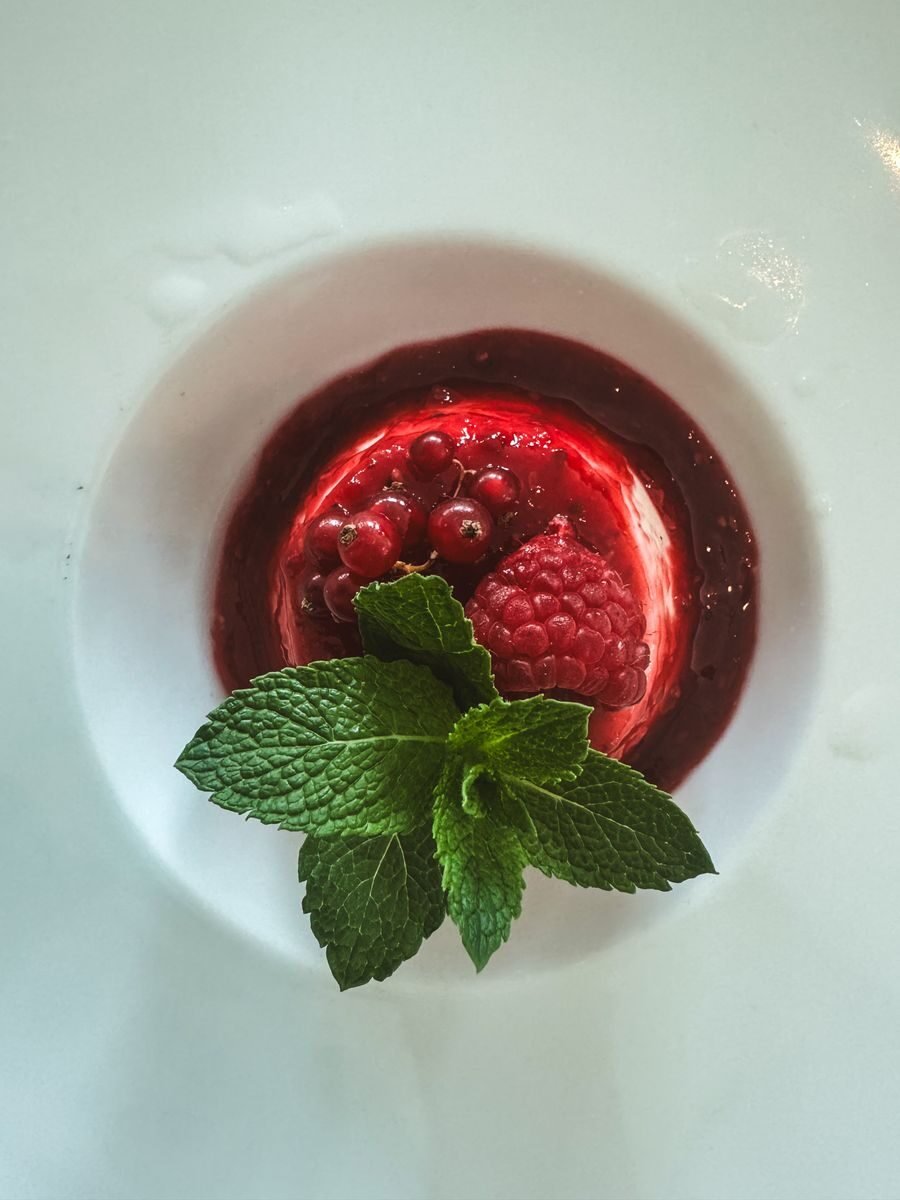 A delectable red berry dessert garnished with fresh mint leaves, captured in a Berlin cafe.